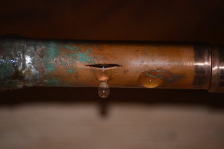 brown pipe burst with corroding, water dripping from burst